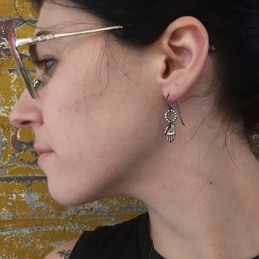 bronze hand earrings with silver circles on top, by Alice Scott on model ear