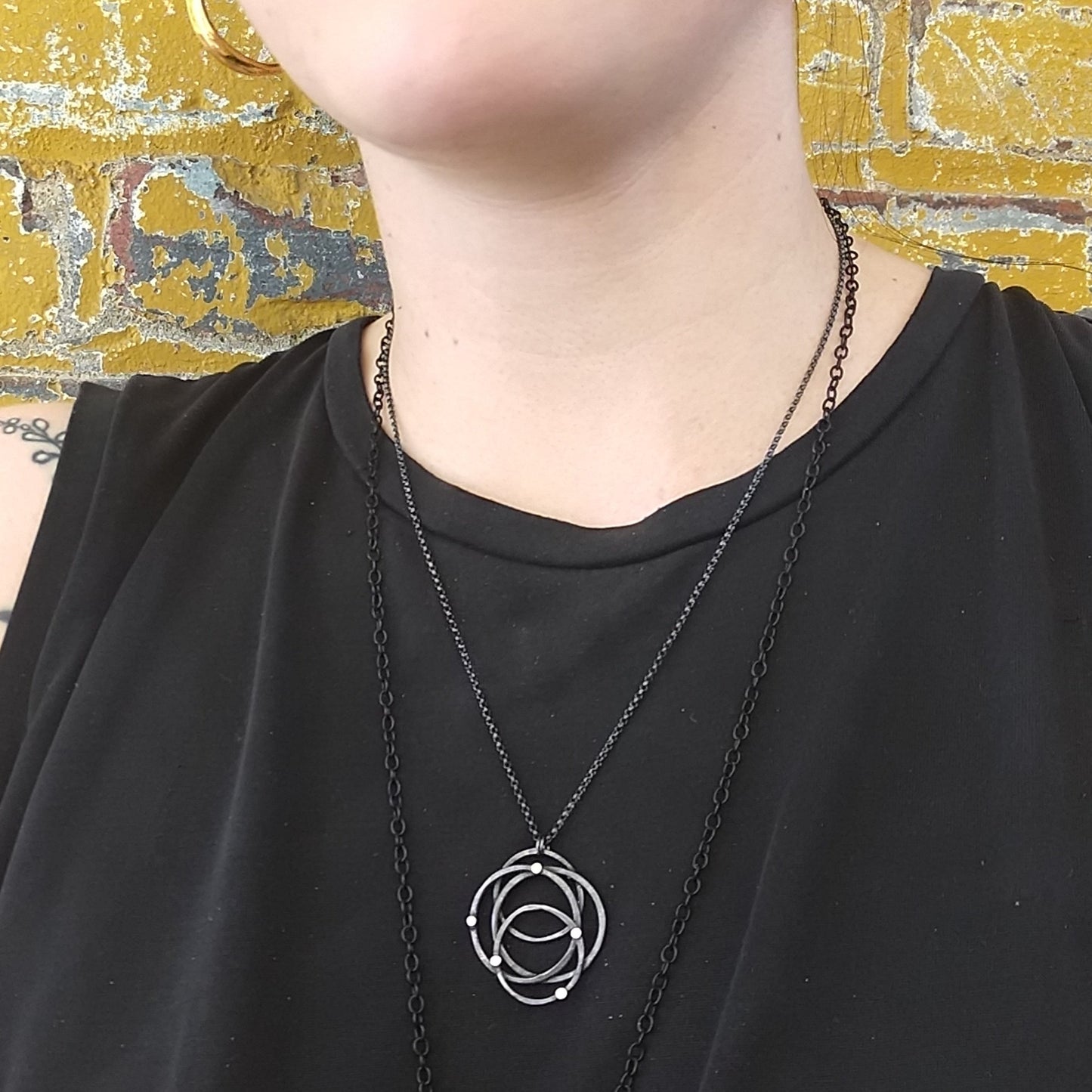 A silver necklace with a hammered galaxy pendant featuring gold dots, displayed on a model, Alice Scott