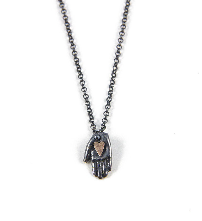 black silver tiny hand necklace with golden heart pendant with silver chain on white background by Alice Scott