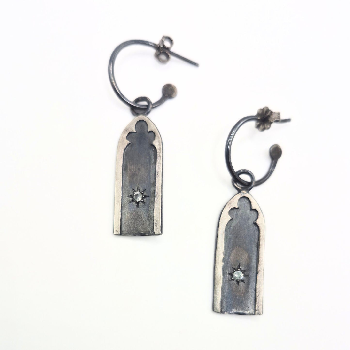 Pair of silver earrings with star set white sapphire stones on a white background by Alice Scott
