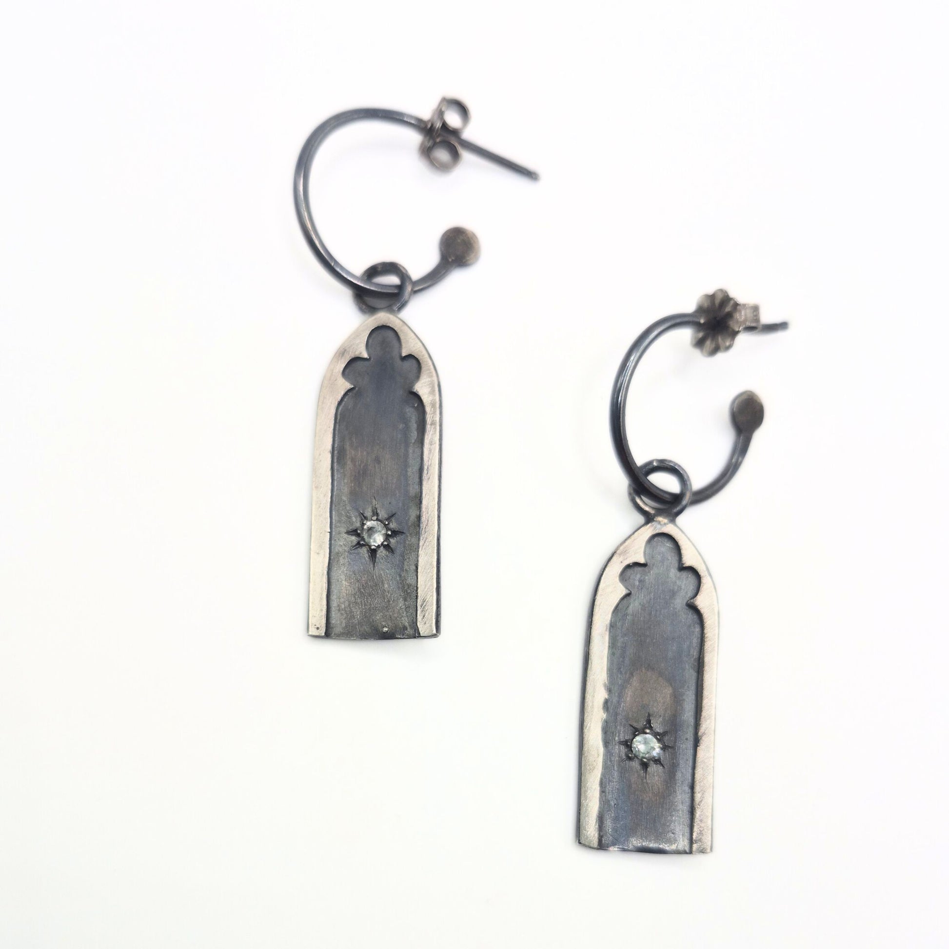 Pair of silver earrings with star set white sapphire stones on a white background by Alice Scott