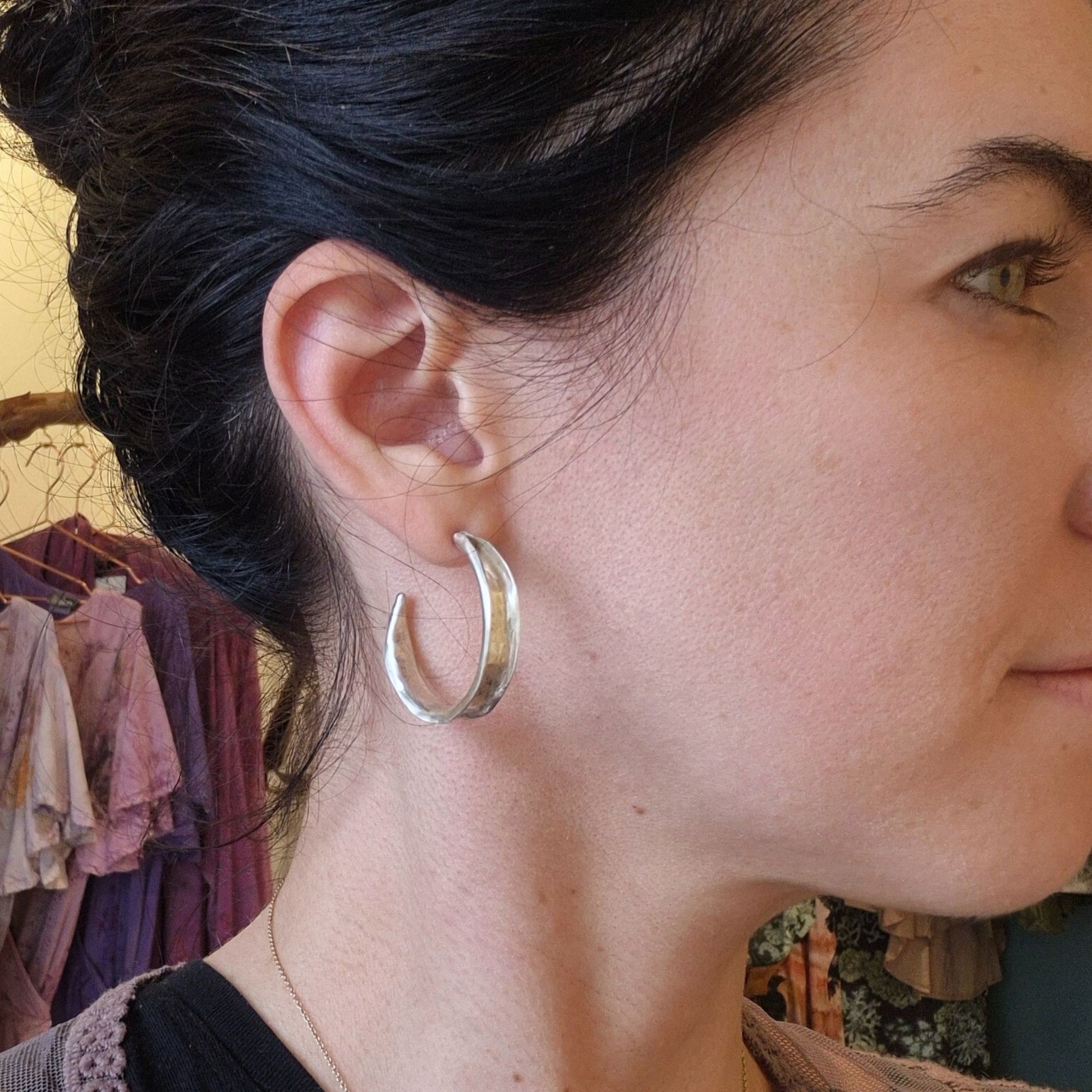 A pair of sterling silver hammered hoop earrings on a model by Alice Scott