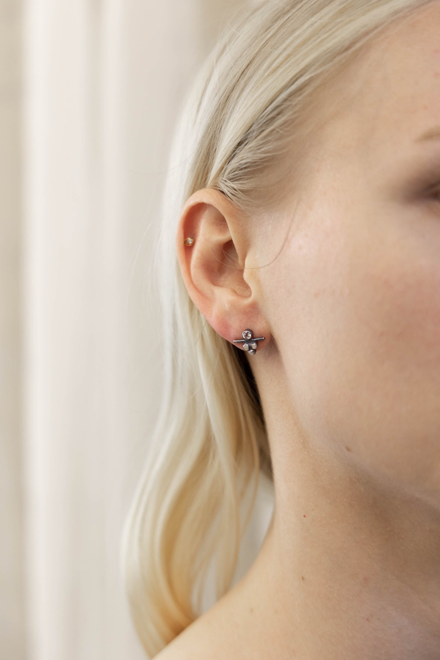 A pair of silver stud earrings with white topaz stones, displayed on a model ear, by Alice Scott