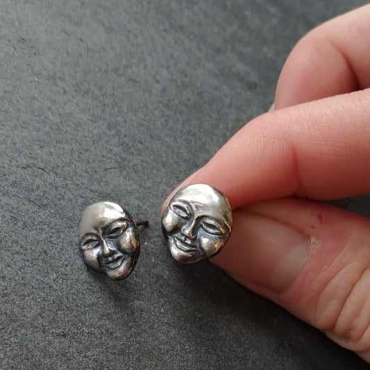 carved face post earrings in silver by Alice Scott on slate background