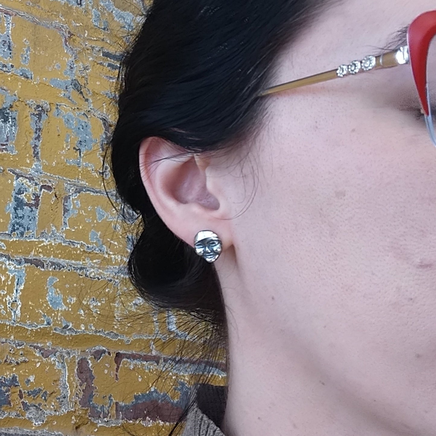 carved face post earrings in silver by Alice Scott on model ear