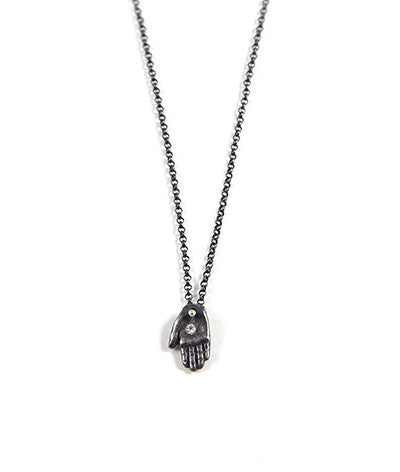 A sterling silver tiny Hamsa necklace with a white sapphire in the palm area, on a sterling silver chain by Alice Scott on a white background.