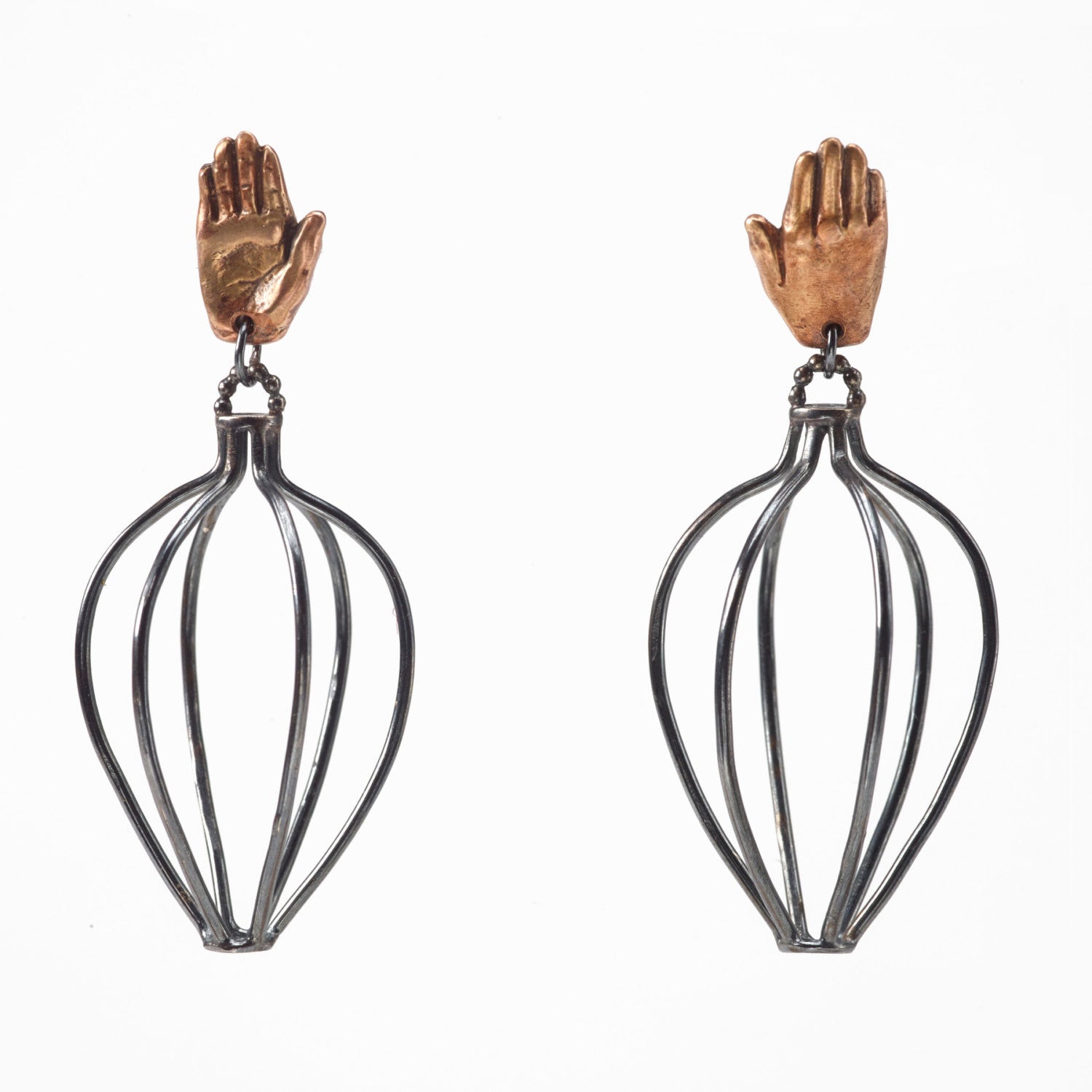 A pair of earrings featuring bronze hands above silver wire vessels with a black patina by Alice Scott